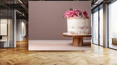 Sweet cake with floral decor on table against color background Wall mural