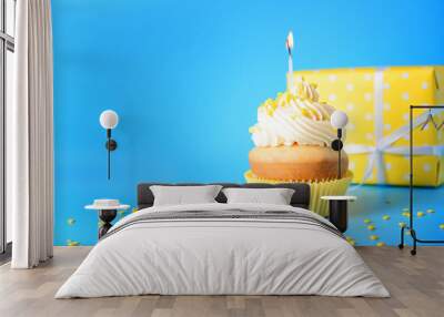 Tasty Birthday cupcake with gift box on color background Wall mural