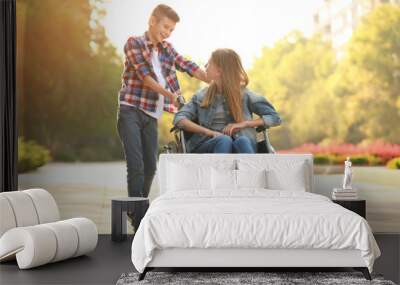 Teenage girl in wheelchair and her brother outdoors Wall mural