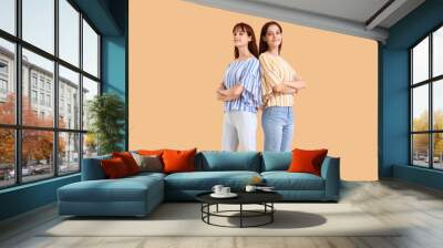 Teenage twin sisters on beige background Wall mural