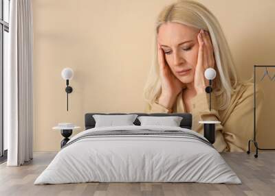 Thoughtful mature woman on beige background, closeup Wall mural