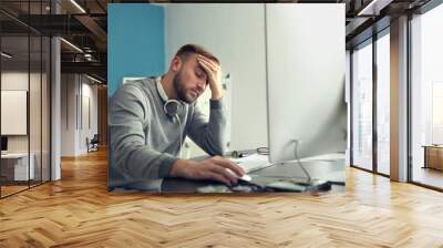 Tired IT specialist working in office Wall mural