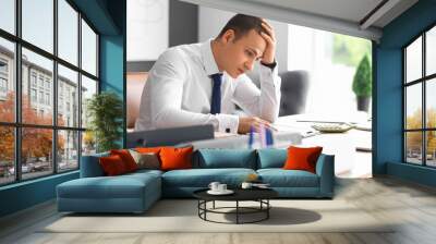 Tired male accountant working at desk in office Wall mural