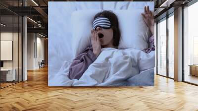 Tired woman with sleep mask in bed at night Wall mural