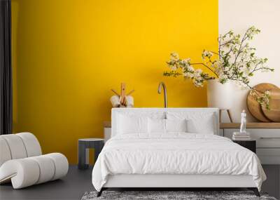 Vase with blooming branches on white counter in yellow kitchen Wall mural