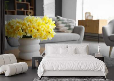 Vase with daffodils and magazine on table in living room, closeup Wall mural