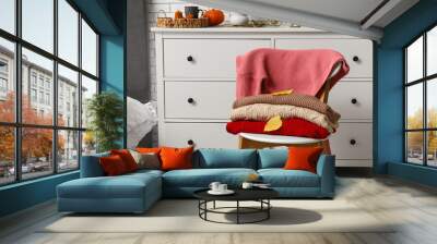 Warm sweaters with autumn leaves on chair in bedroom Wall mural