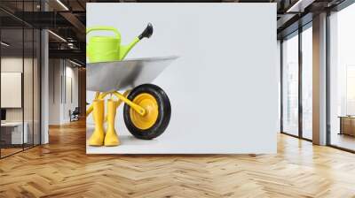 Wheelbarrow with plant and gardening supplies on light background with space for text Wall mural