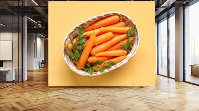 Wicker bowl with fresh carrots on orange background Wall mural