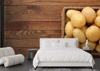 Wicker box with raw potatoes on wooden background Wall mural