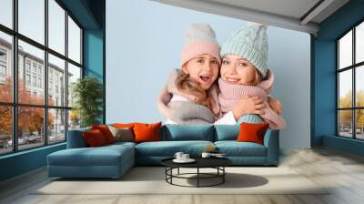 Woman and her little daughter in winter clothes on color background Wall mural