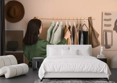 Woman and rack with stylish autumn clothes in dressing room Wall mural