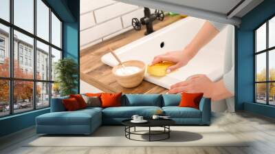 Woman cleaning white sink with sponge and baking soda Wall mural