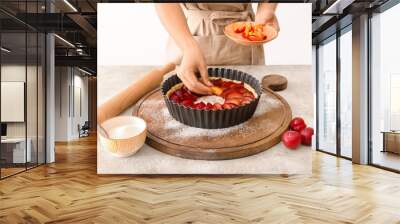 Woman cooking plum pie at table Wall mural