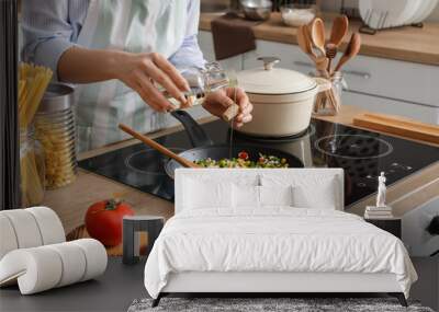 Woman cooking tasty rice with vegetables on stove in kitchen, closeup Wall mural