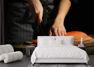 Woman cutting fillet of fresh salmon at table Wall mural