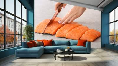 Woman cutting fillet of fresh salmon at table Wall mural