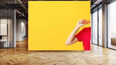 Woman eating healthy carrot on yellow background with space for text. Diet concept Wall mural