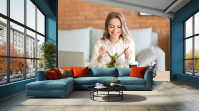 Woman eating healthy vegetable salad in office Wall mural