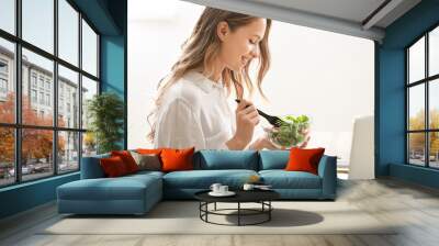 Woman eating healthy vegetable salad in office Wall mural