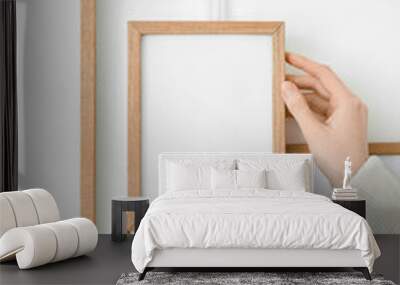 Woman hanging blank photo frame on light wall, closeup Wall mural