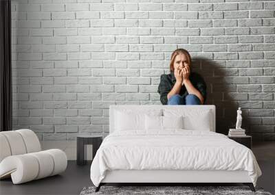 Woman having panic attack while sitting near brick wall Wall mural