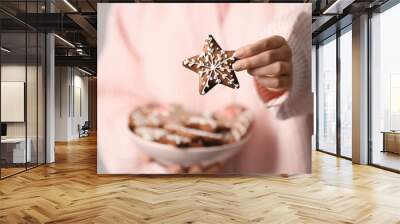 Woman holding Christmas gingerbread cookie on grey background, closeup view Wall mural