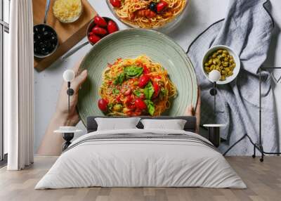 Woman holding plate with tasty Pasta Puttanesca at table Wall mural