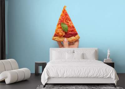 Woman holding slice of tasty pizza on blue background Wall mural