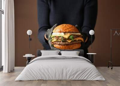 Woman holding tasty burger on color background Wall mural