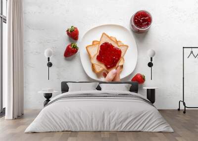 Woman holding tasty toast with strawberry jam on grunge white background Wall mural