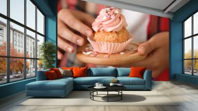 Woman holding wooden board with delicious cupcake, closeup Wall mural