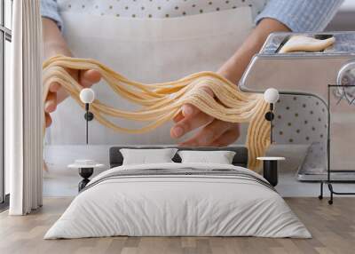 Woman making pasta with machine in kitchen, closeup Wall mural