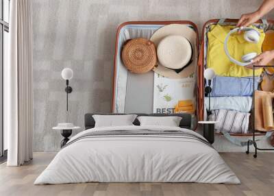 Woman packing suitcase at home, top view. Travel concept Wall mural