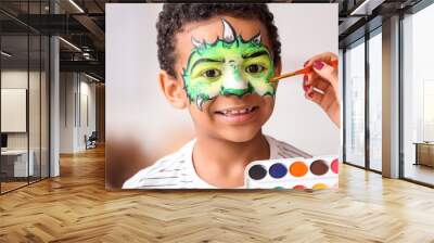 Woman painting face of African-American boy at home Wall mural