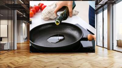 Woman pouring olive oil onto frying pan in kitchen Wall mural