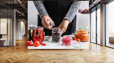 Woman preparing beetroot for fermentation at table in kitchen Wall mural