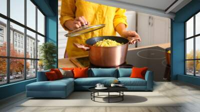 Woman preparing pilaf in cooking pot, closeup Wall mural