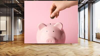 Woman putting money in piggy bank on color background Wall mural