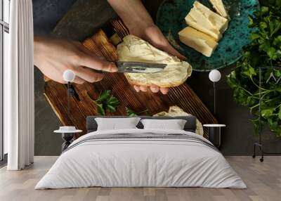 Woman spreading tasty bread with butter at table Wall mural