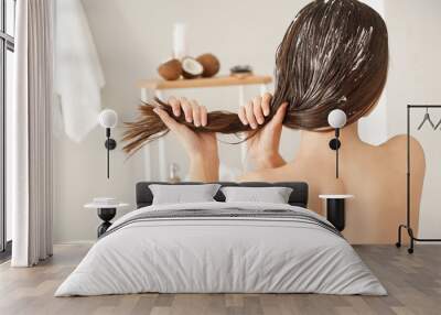 Woman using coconut oil for hair in bathroom Wall mural