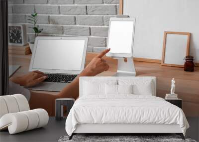 Woman using modern laptop and tablet computer on wooden standing desk Wall mural