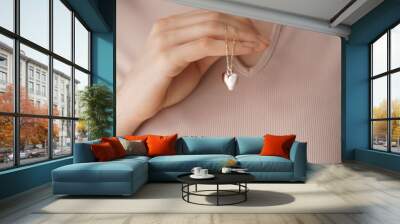 Woman wearing heart-shaped pendant, closeup Wall mural