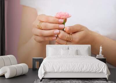 Woman with beautiful manicure and stylish jewelry holding beautiful carnation flower on color background Wall mural