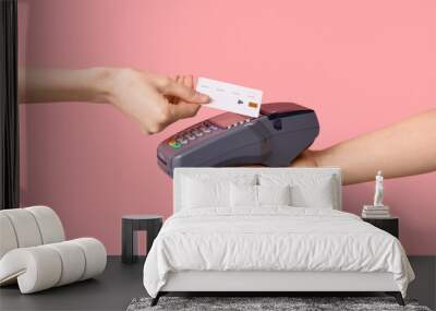 Woman with credit card paying via payment terminal on pink background Wall mural