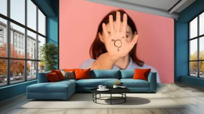 Woman with drawn symbol of transgender on her palm against color background Wall mural