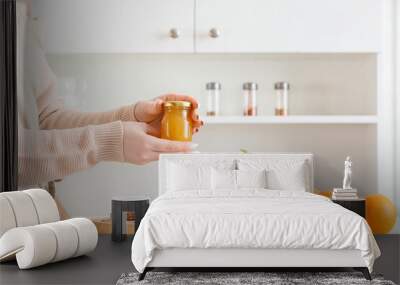 Woman with jar of tasty orange jam in kitchen Wall mural