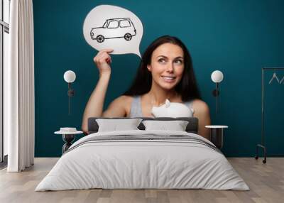 Woman with piggy bank dreaming about new car on color background Wall mural