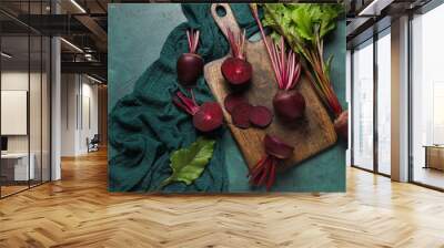 Wooden board of fresh beets with leaves on green background Wall mural