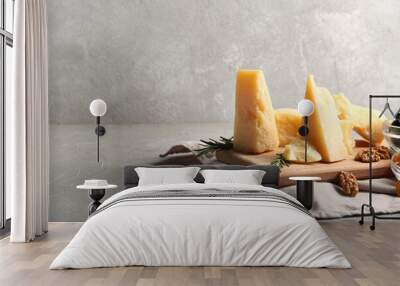 Wooden board with pieces of tasty Parmesan cheese on grey background Wall mural